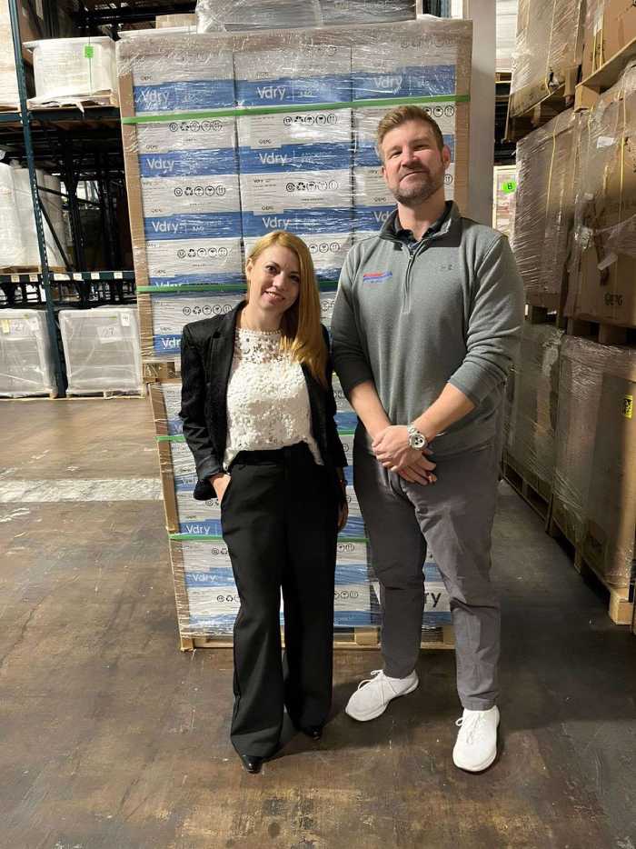 Warehouse professionals standing in front of stacked pallets in a logistics facility, showcasing expertise in inventory management and efficient storage solutions.